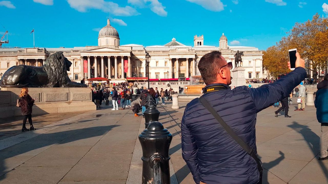 People in Trafalgar Square on a sunny day, the domed National Gallery building behind