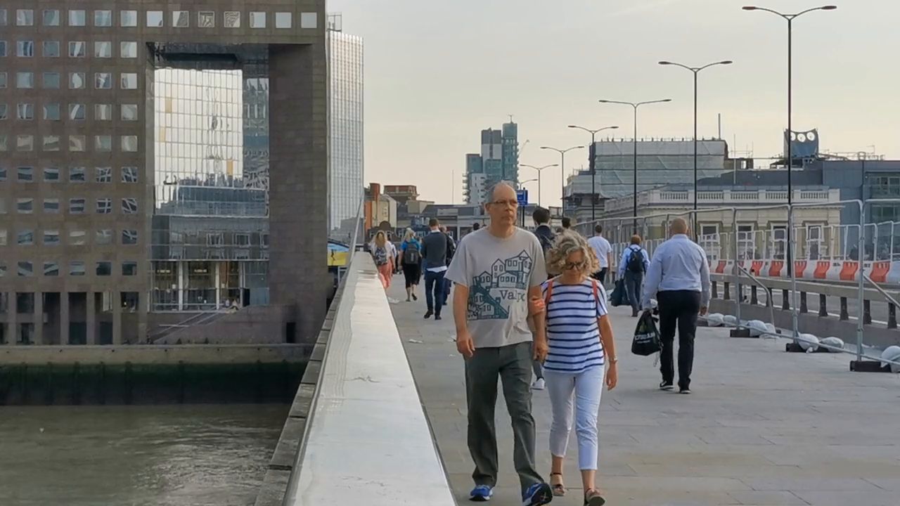 People walking along the pavement of London Bridge on a grey day